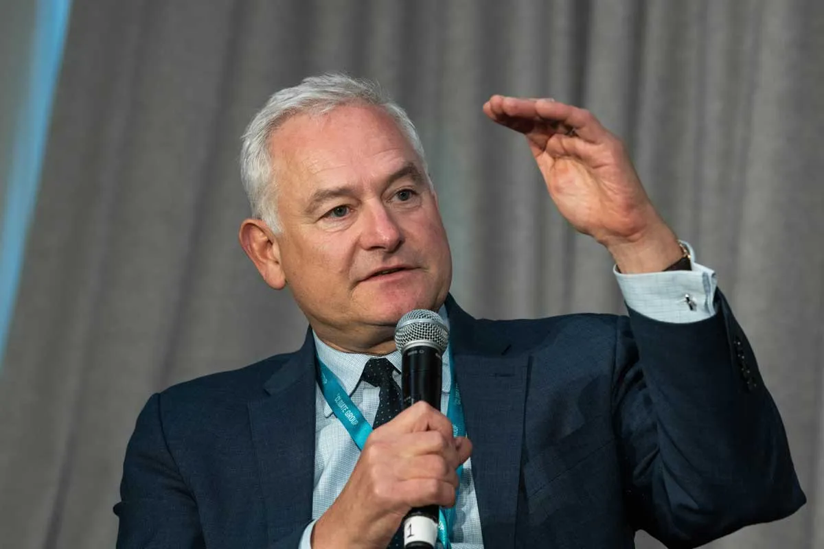 Rear view of a man wearing a green safety helmet and striped shirt standing in front of solar panels.